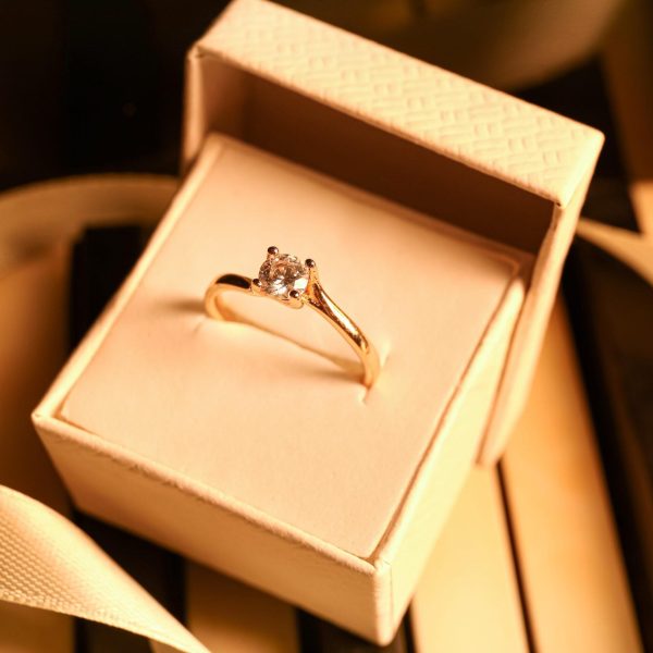 Box with engagement ring and ribbon on piano keys, closeup